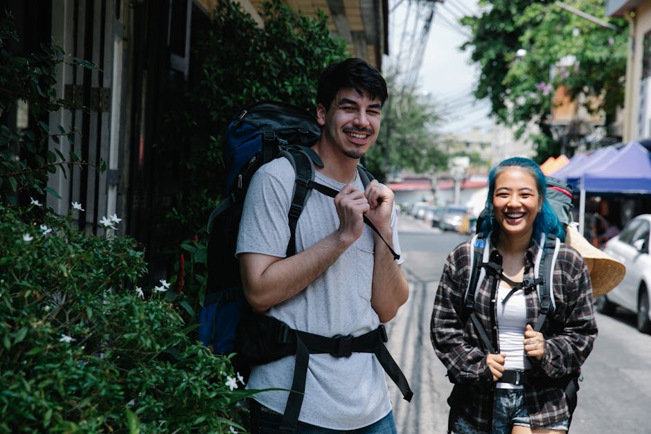Two joyful backpackers exploring a vibrant city street on a sunny day, capturing travel adventure.