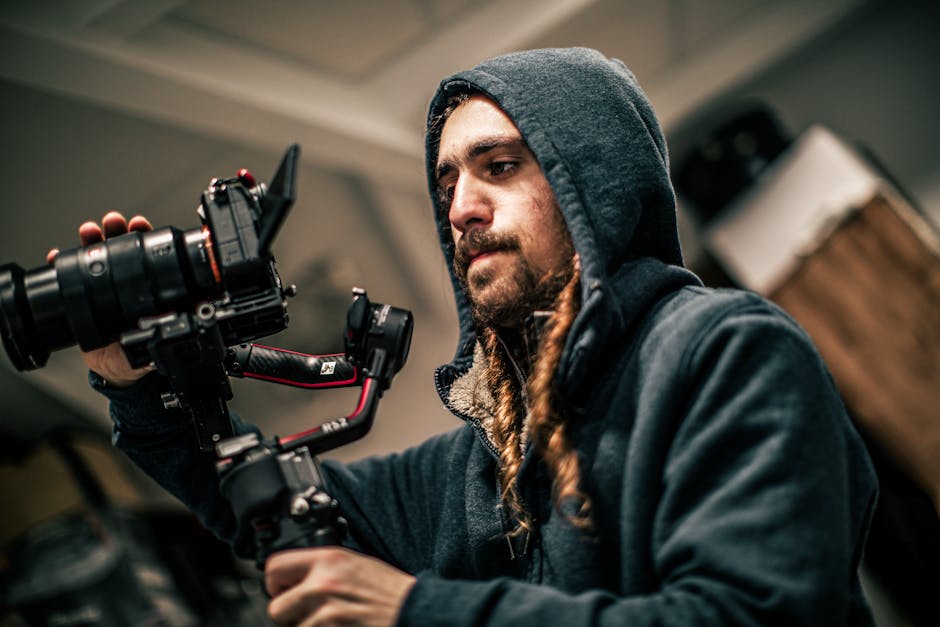 A focused cameraman in a hoodie skillfully handles a camera gimbal indoors.
