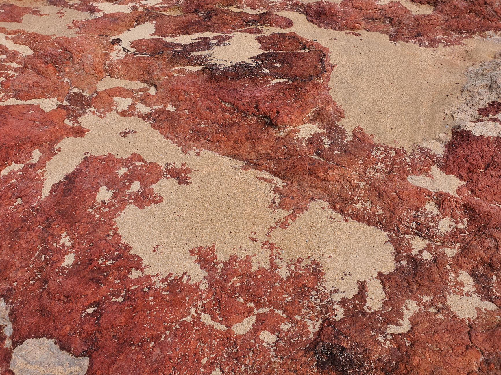 Close-up of red rock formation with sand patches in Newhaven, Australia.