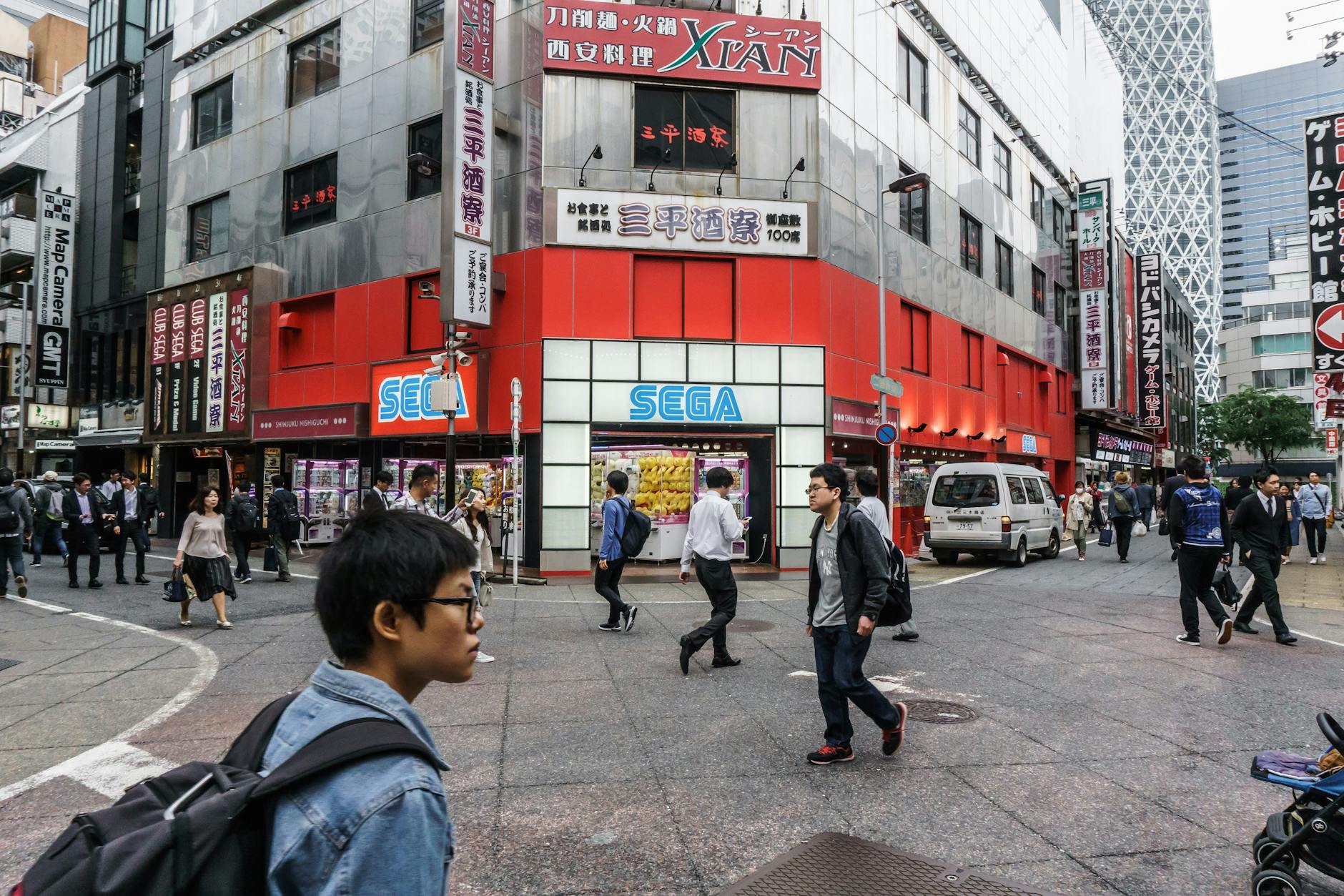 Busy Shinjuku street scene with people walking past a Sega store in Tokyo's bustling urban landscape. – SEGA sale price vs