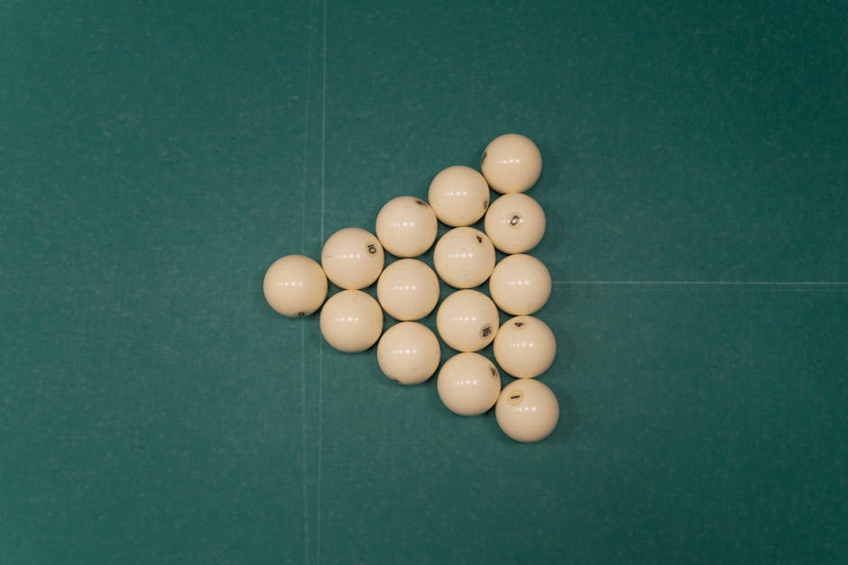 Flat lay of triangle arrangement of billiard balls on a green billiard table, ready for a game.