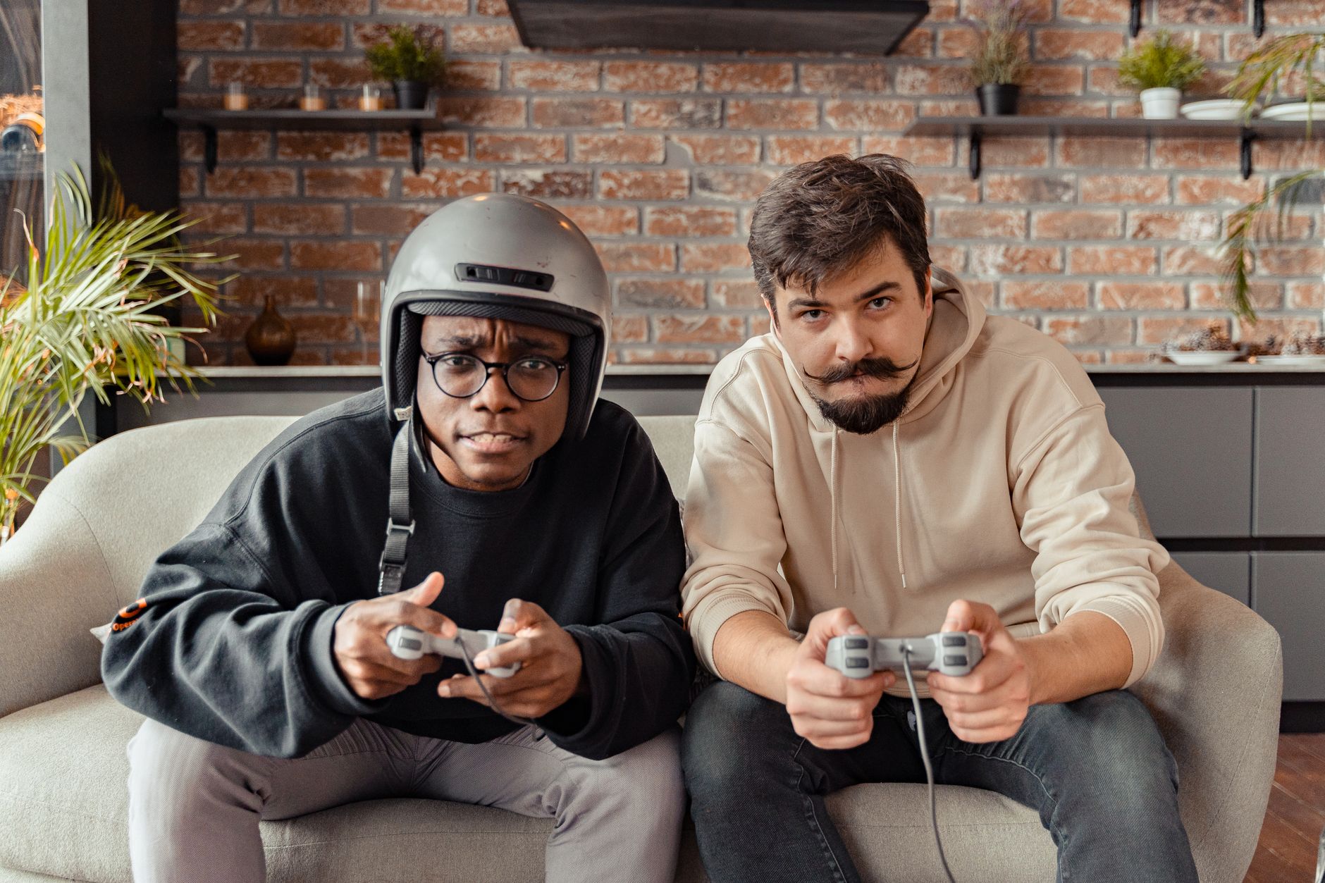 Two friends intensely gaming on a couch indoors, enjoying quality time together.