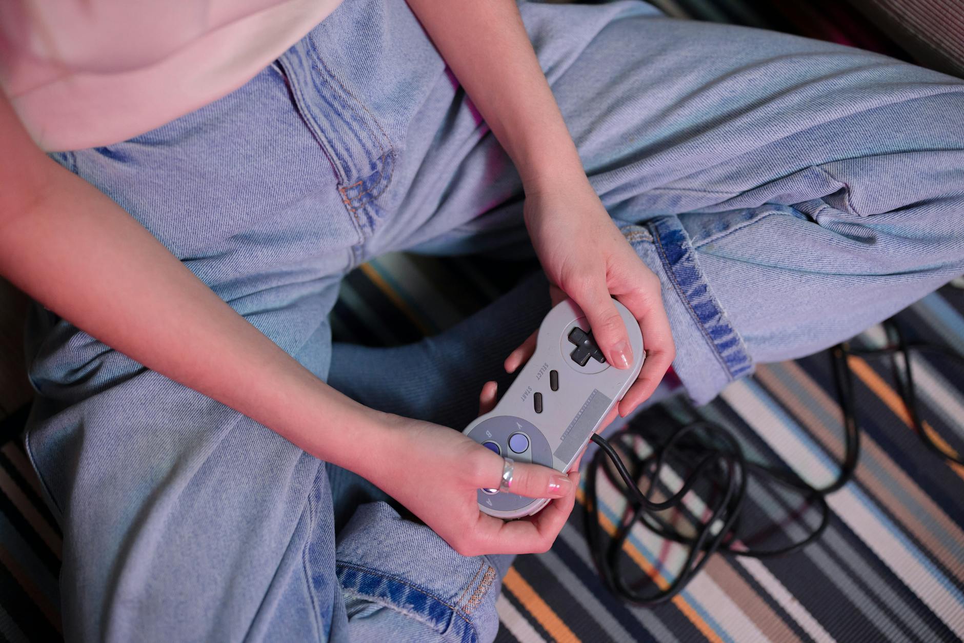 Close-up of a young woman holding a retro game controller indoors, enjoying gaming. – i need game hold