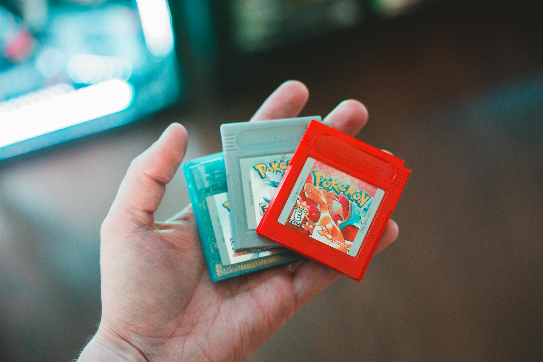 Hand holding vintage Pokemon game cartridges, showcasing nostalgic gaming. – GamesRecap.io game announcements