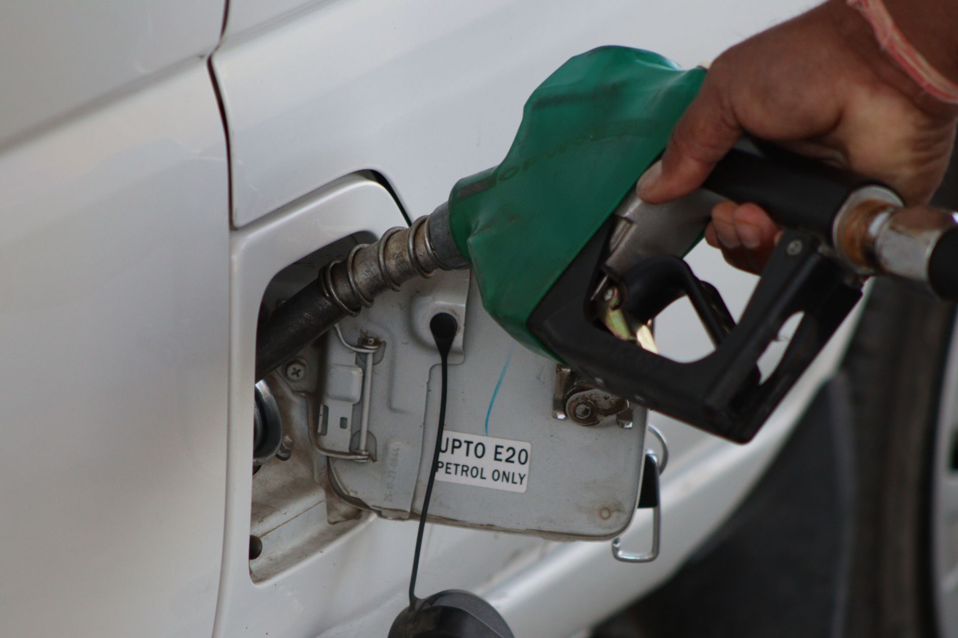 Close-up of a hand refueling a vehicle. E20 petrol pump nozzle in use. – MSI MAG 275QF E20