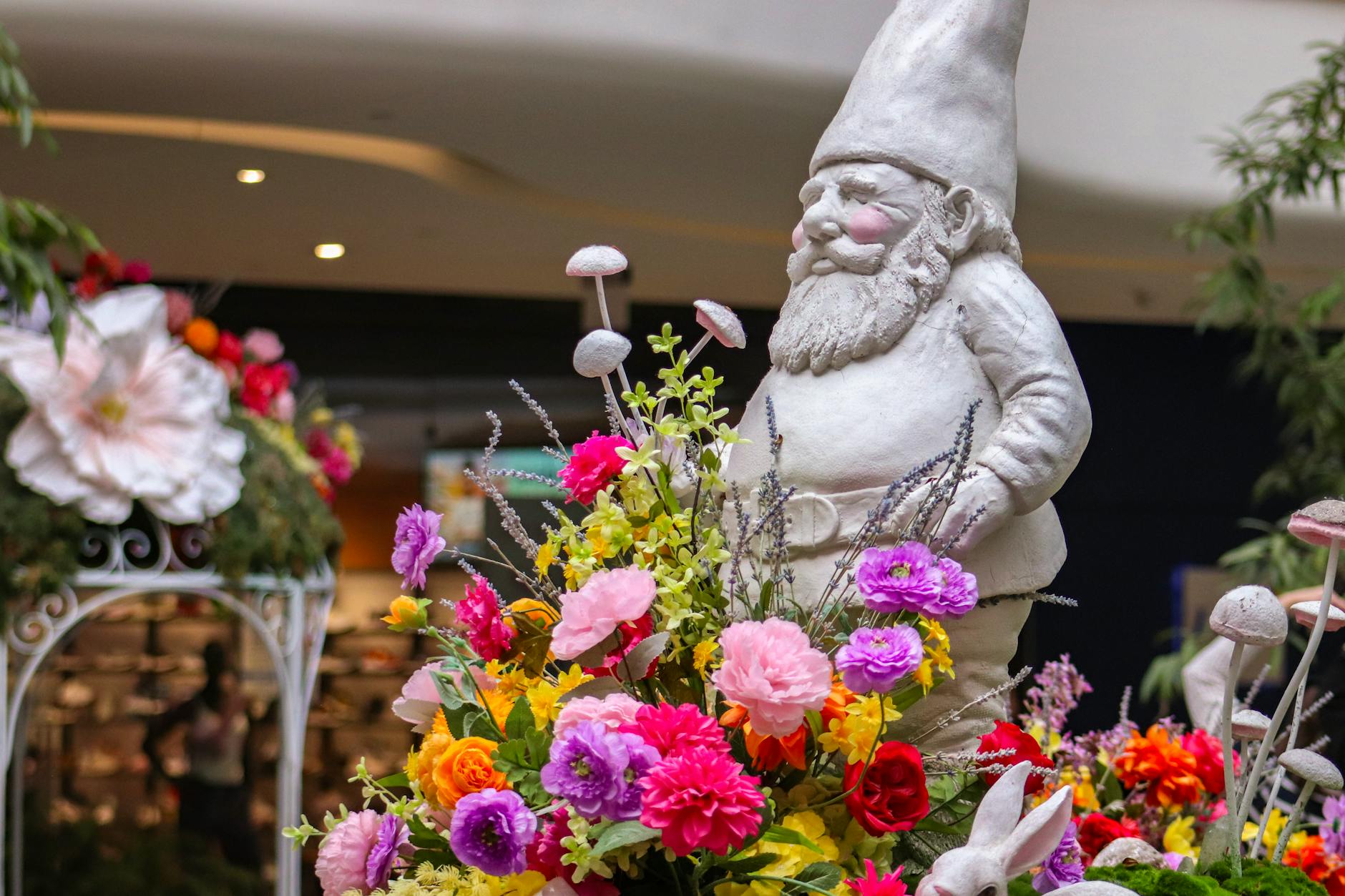 A playful indoor garden scene with a gnome surrounded by vibrant flowers and mushrooms.