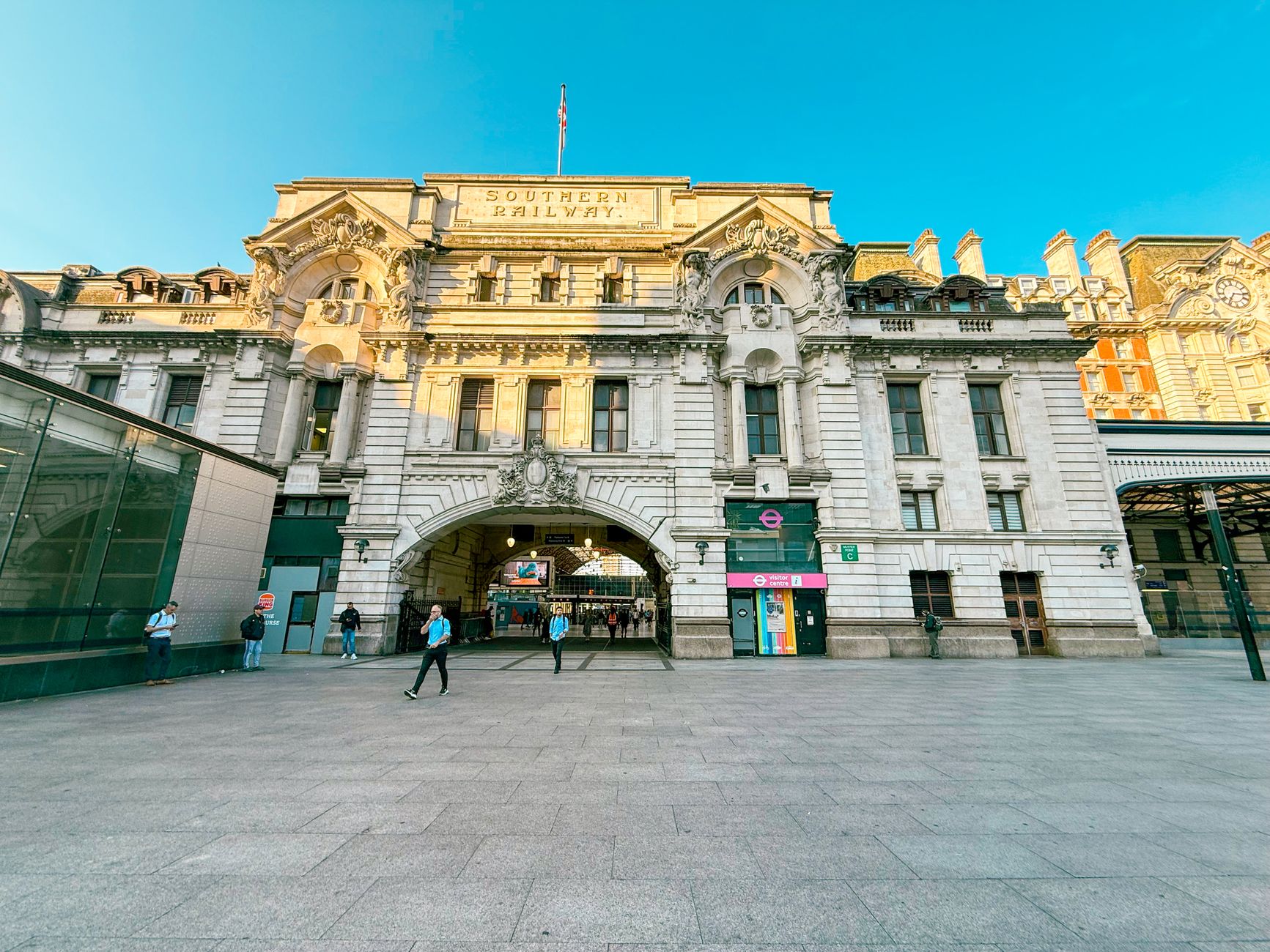 View of the historic Victoria Station facade in London under a clear blue sky.
