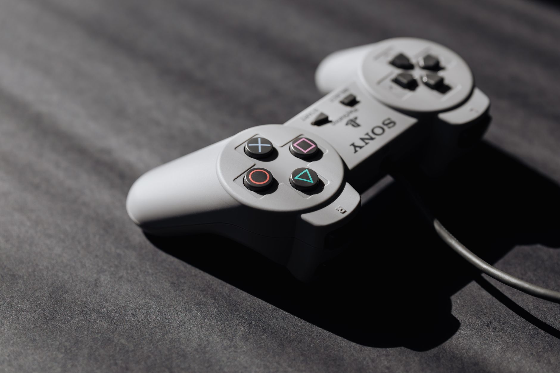 Retro Sony game controller with classic buttons on a textured dark surface, showcasing vintage electronics.